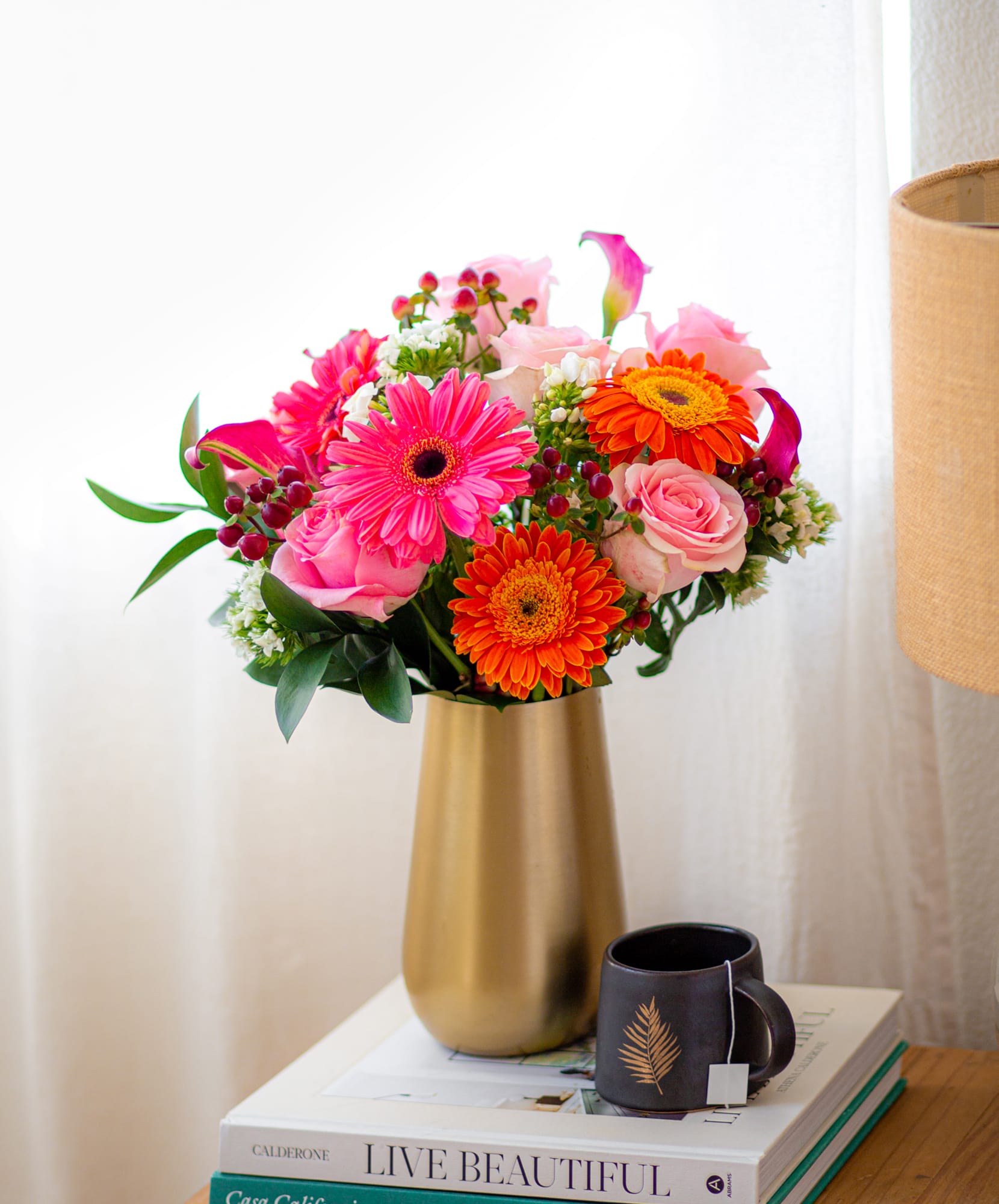 Bright and vibrant floral arrangement featuring pink gerbera daisies, roses, and orange blooms.